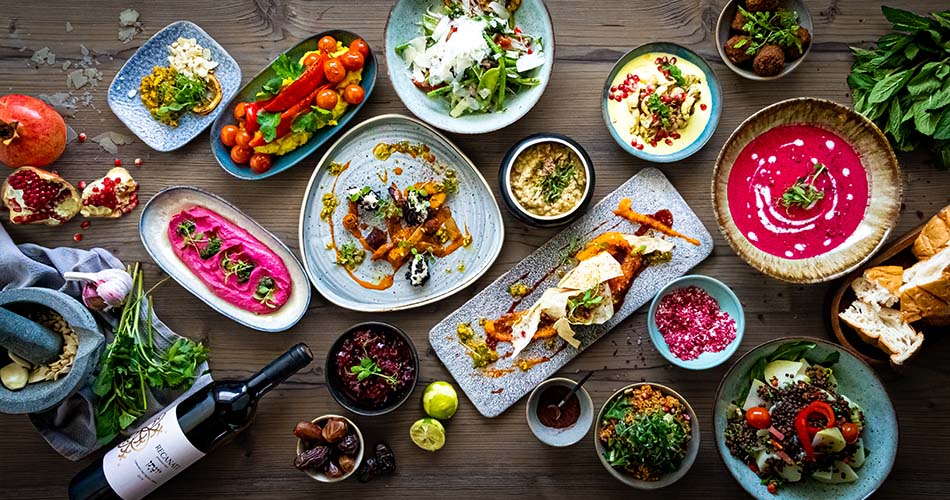 Delikatessen kategorie Verschiedene Delikatessen angerichtet auf bunten Tellern auf einem Holztisch