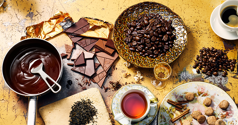 Frischer Tee und Kaffeebohnen auf einem Holztisch dazu beiliegend verschiedene Desserts